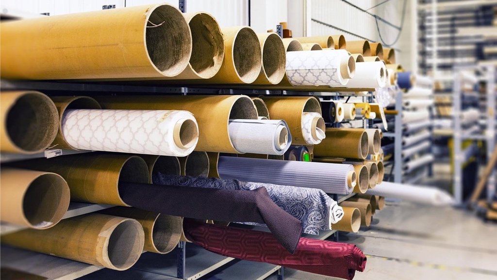 Diseñador de moda revisando rollos de tela y opciones de fabricación